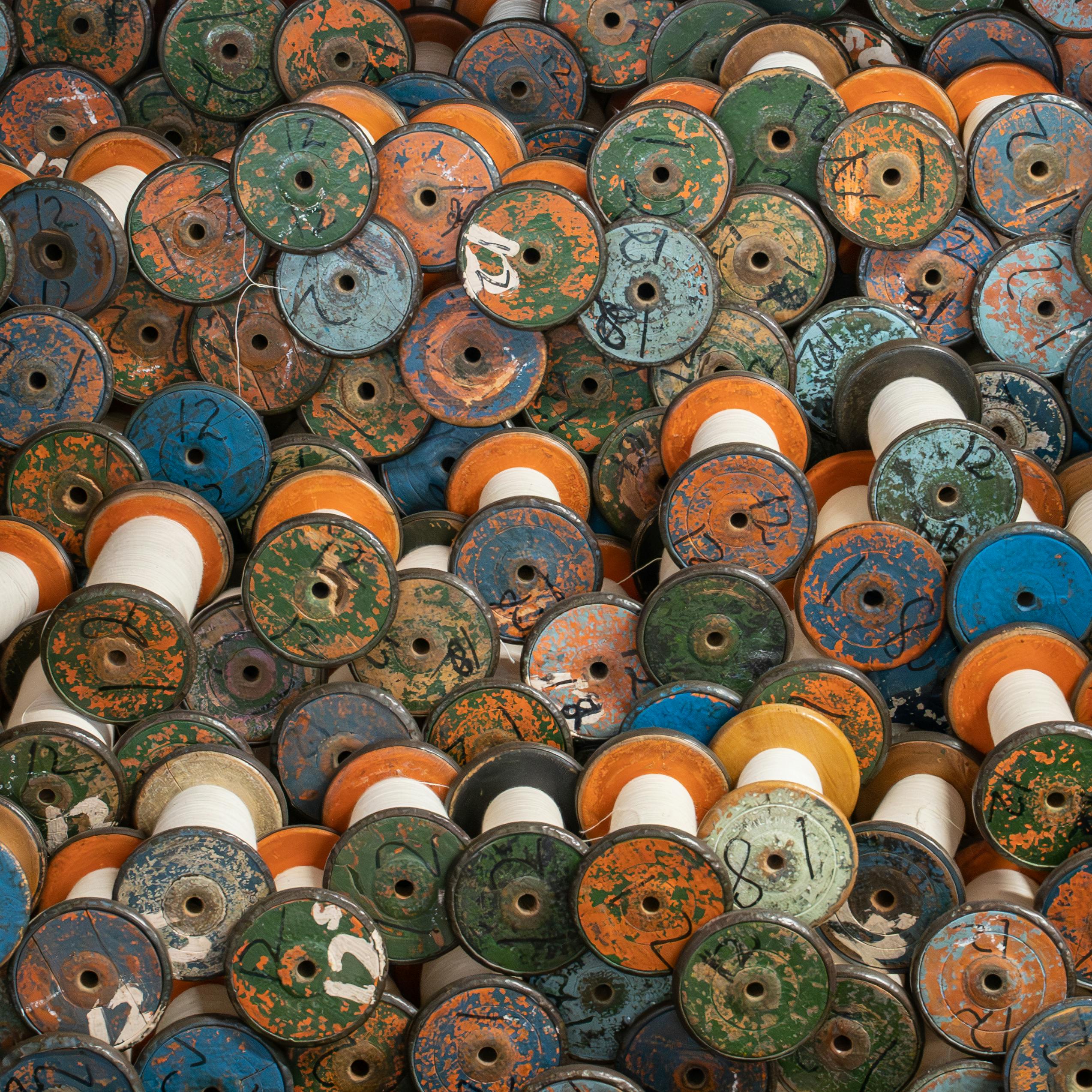 A vibrant collection of vintage industrial spools with threads, showcasing a colorful and textured pattern.