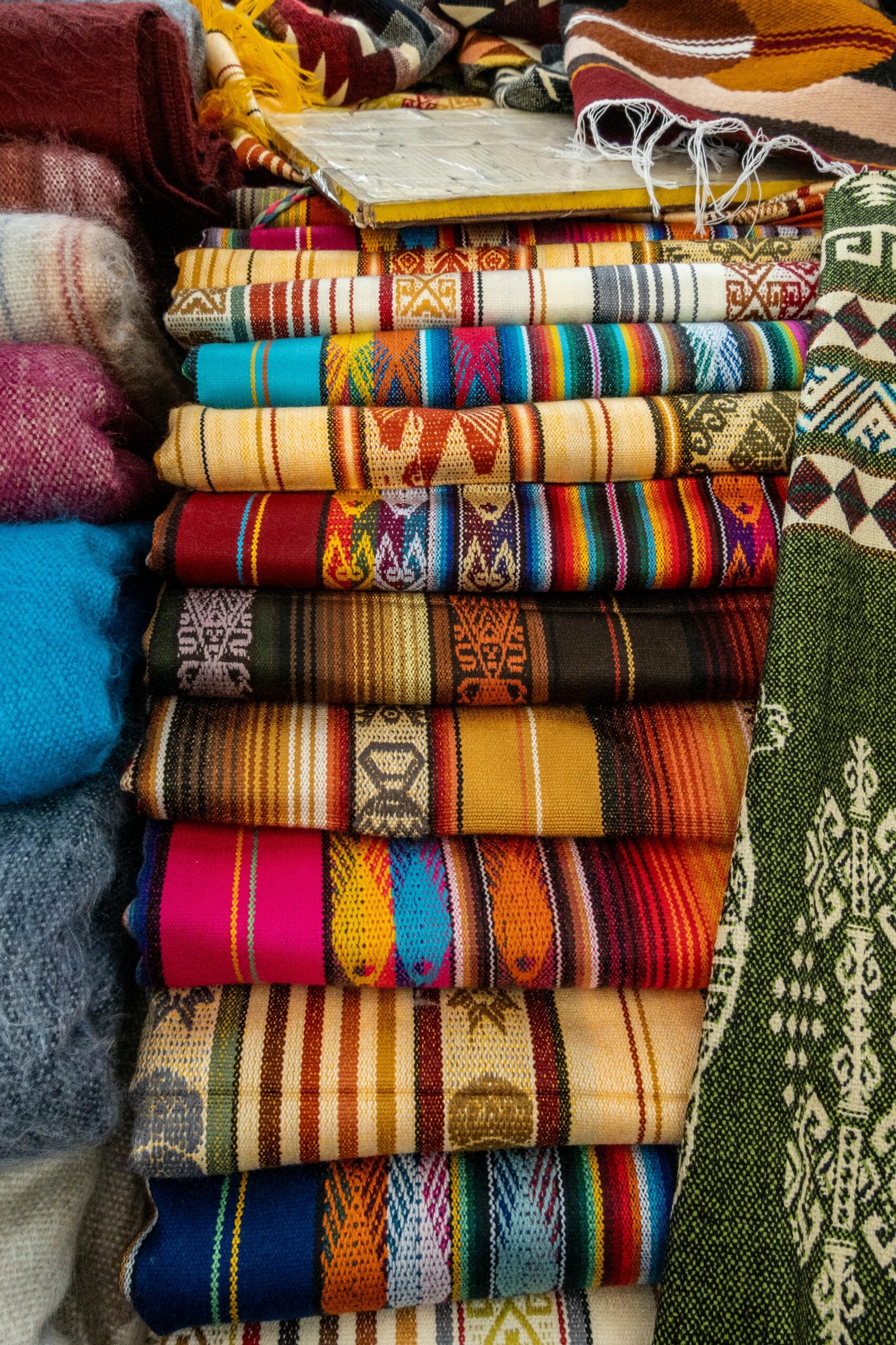 Colorful stack of traditional handwoven textiles showcasing intricate patterns and vivid hues.